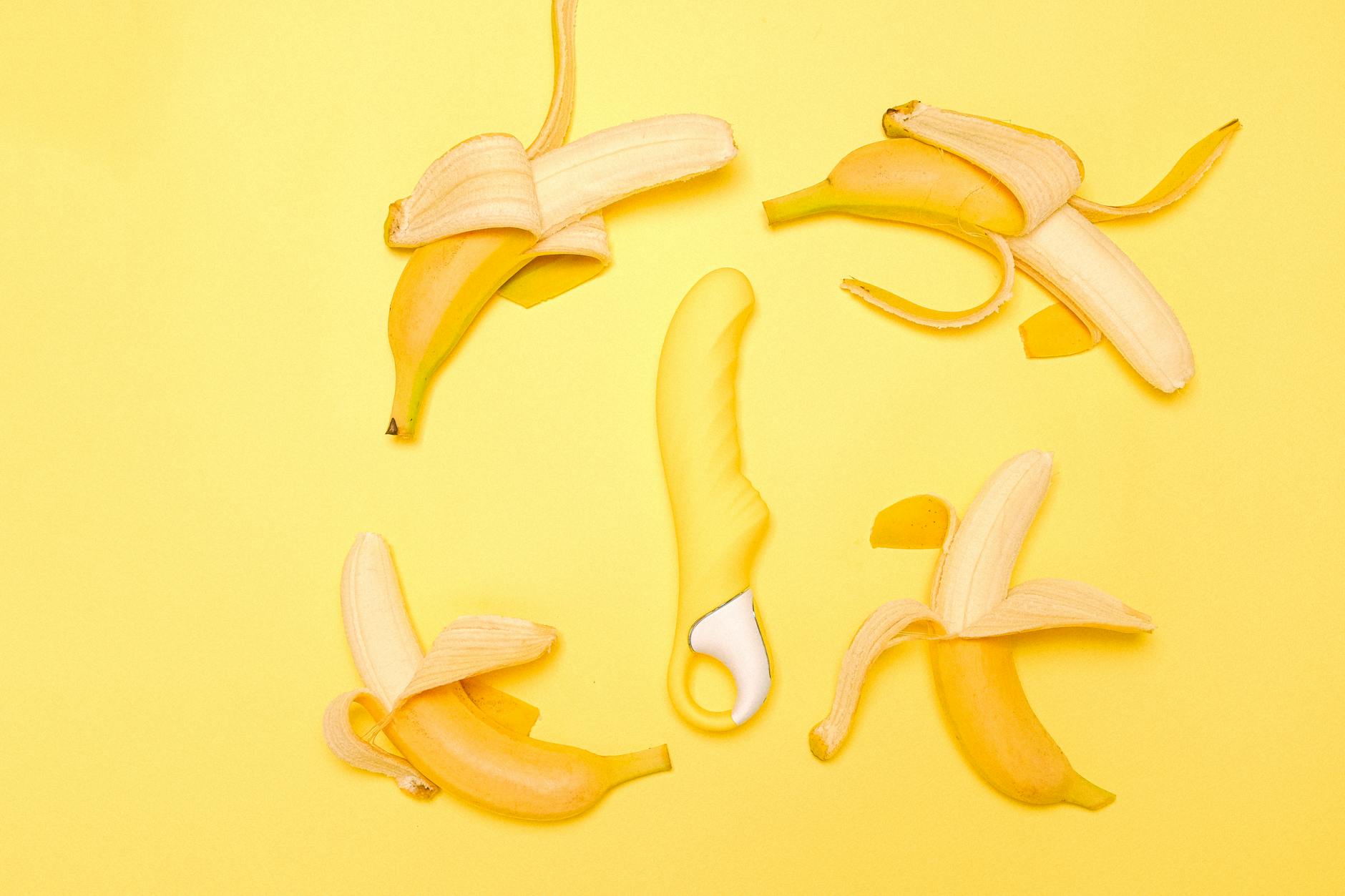 Yellow clitoral vibrator displayed with fresh lemons on a bright yellow background