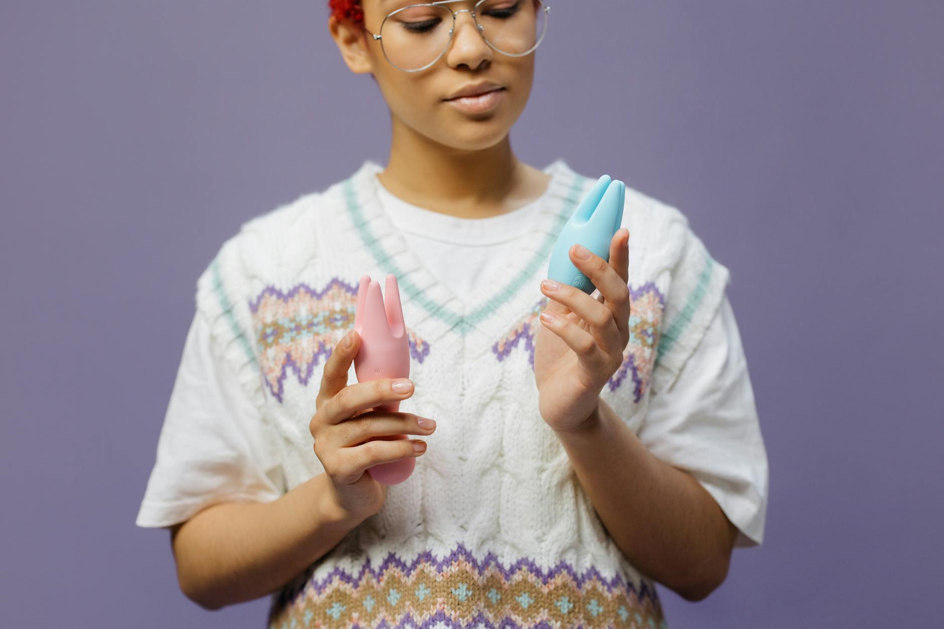 Woman holding and examining a lemon clitoral vibrator with contemplative expression