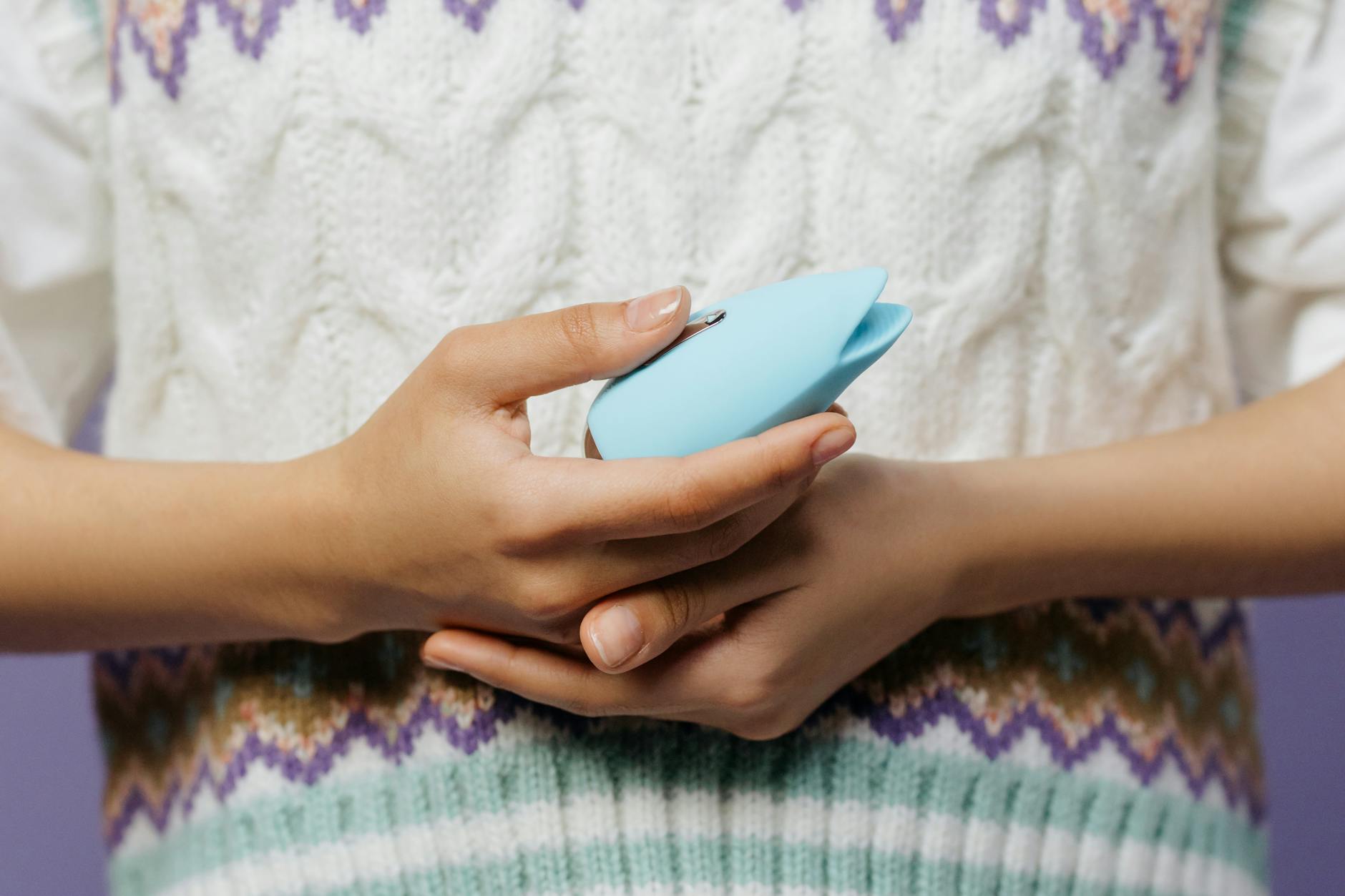 Close-up of hands holding lemon clitoral vibrators in shades of blue and pink