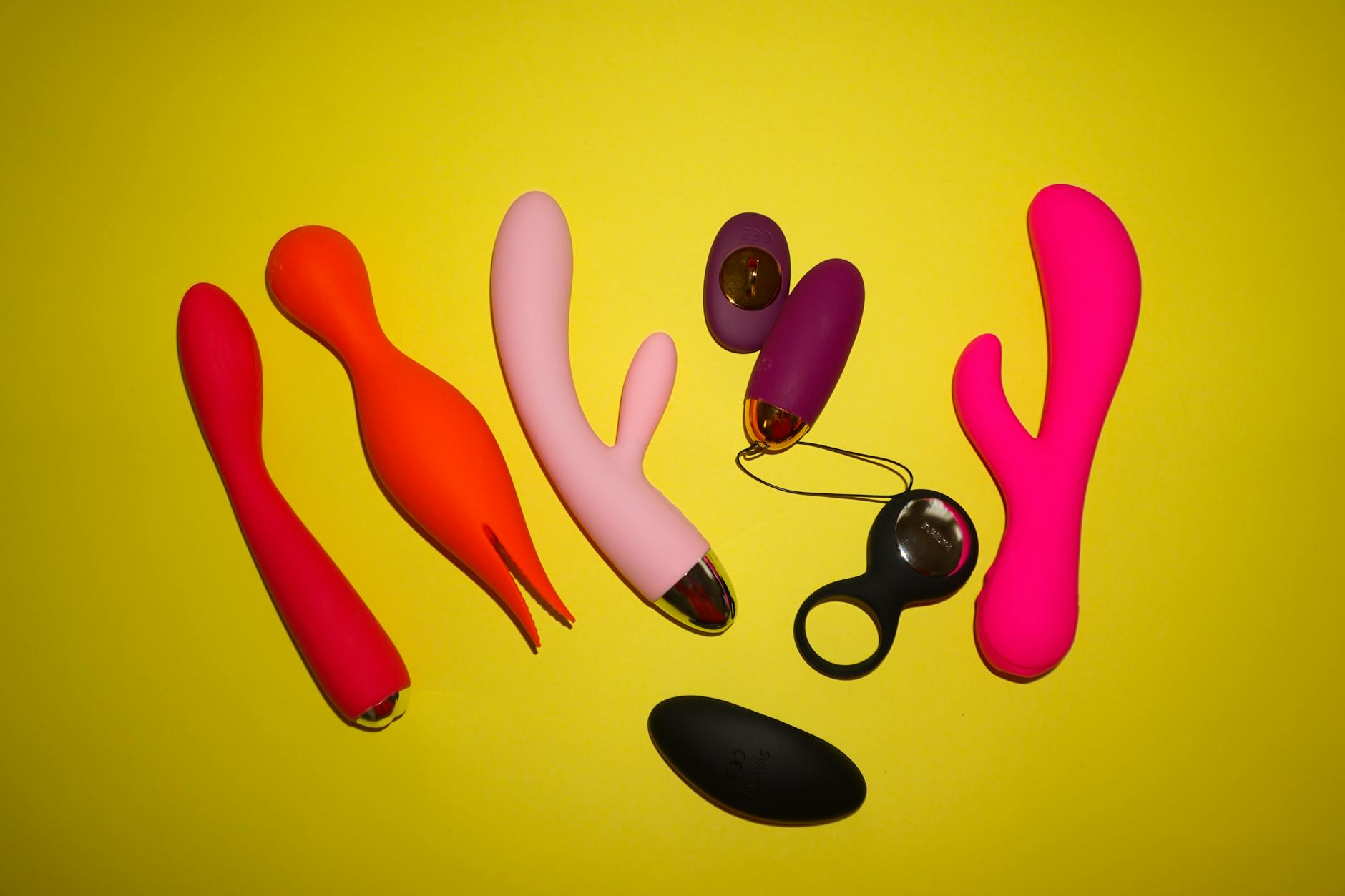 Woman holding two colorful vibrators against a purple background, exploring pleasure options